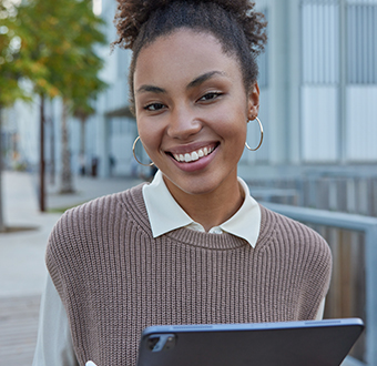 a woman smiles while holding a tablet computer