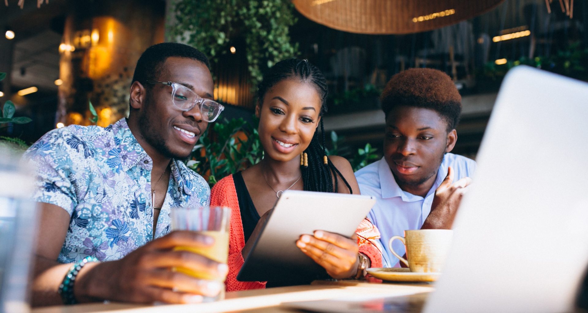 three people sitting at a table looking at a laptop
